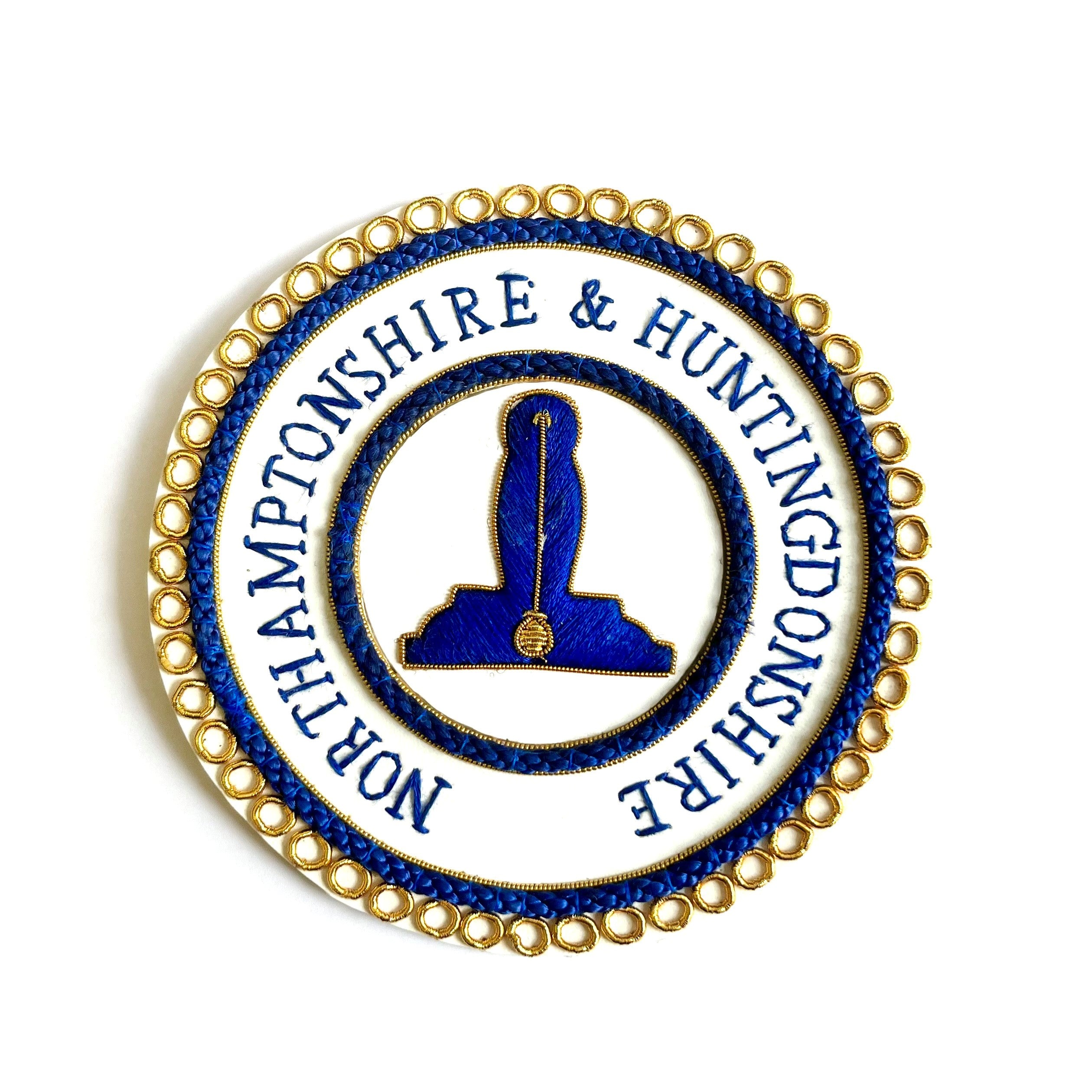 A gold/blue-colored Masonic apron badge with embroidered text and a symbol in the center.