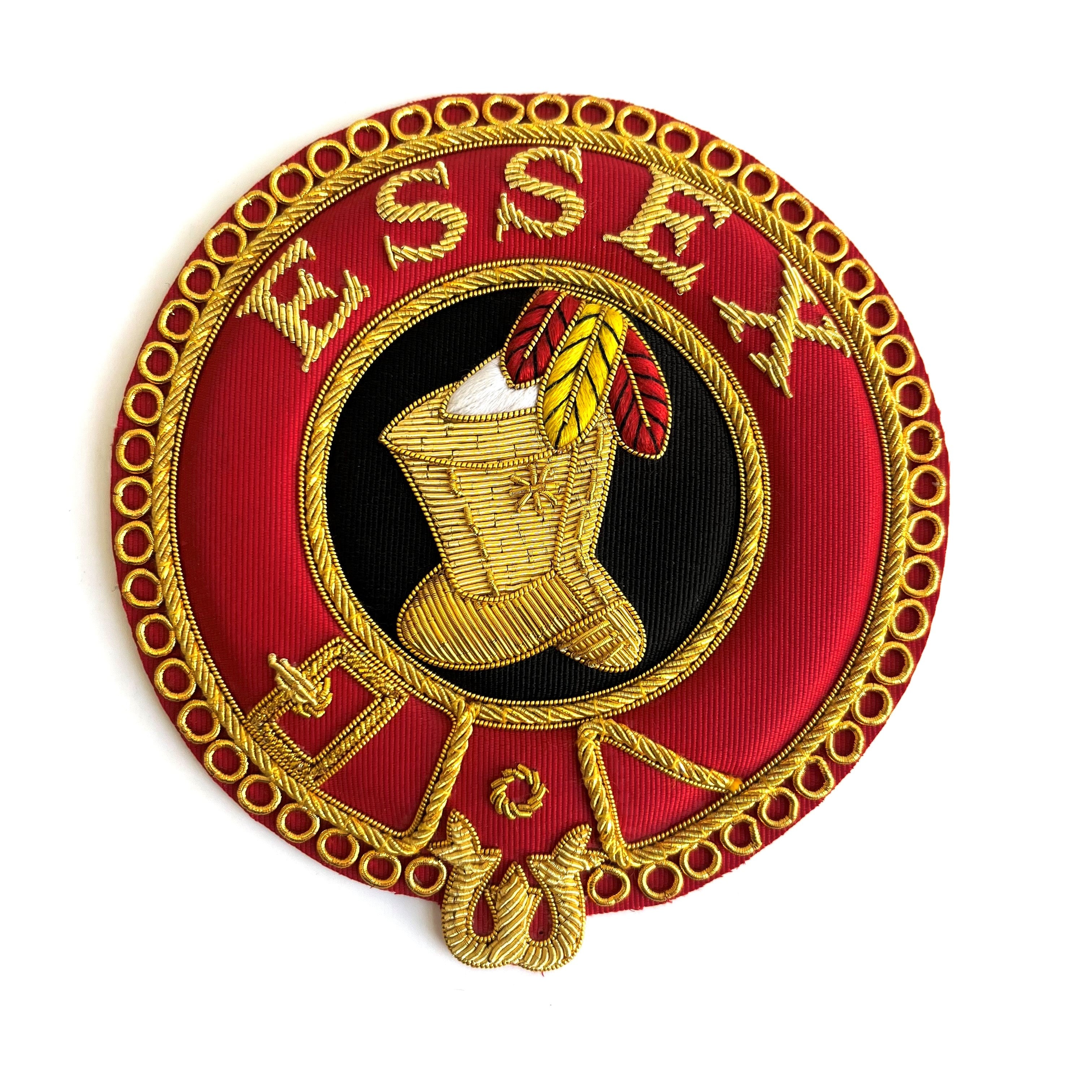 A circular red, gold, black, and white embroidered badge with the word 'ESSEX' in the center and a figure wearing a boot and holding a arrow.