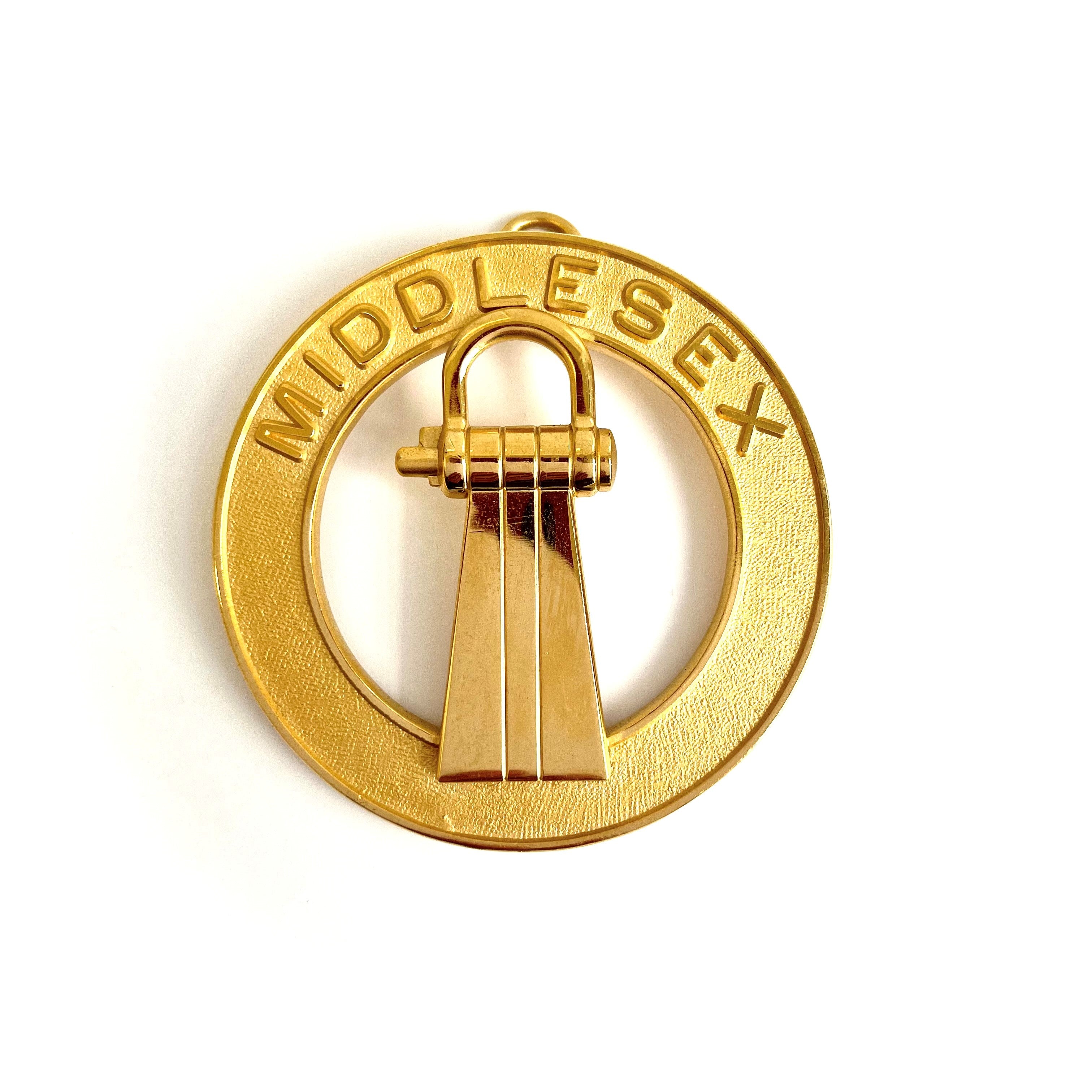 A gold-coloured metal collar jewel with the inscription 'MIDDLESEX' and a Masonic symbol in the center.
