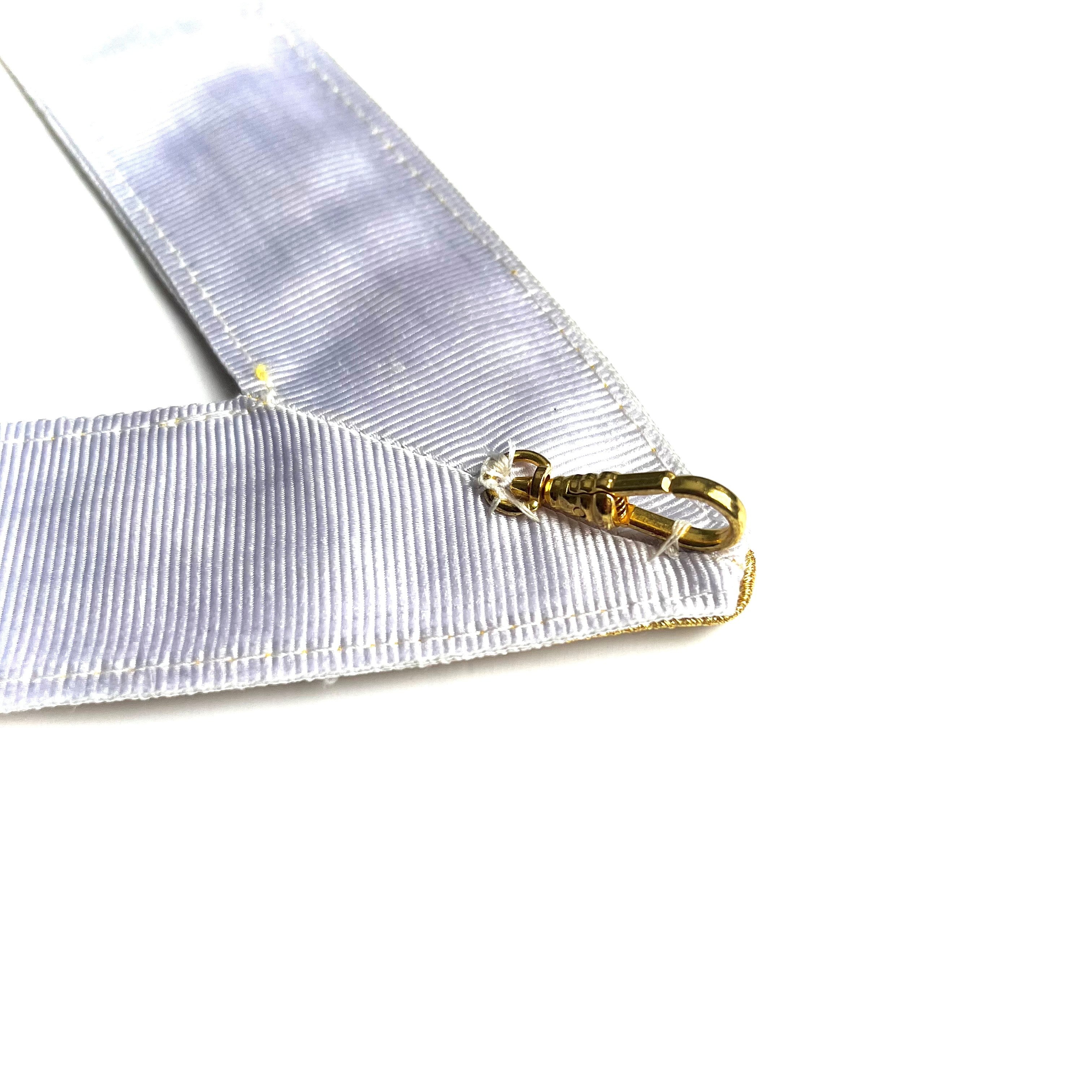 White ribbon with a gold clasp on a white background