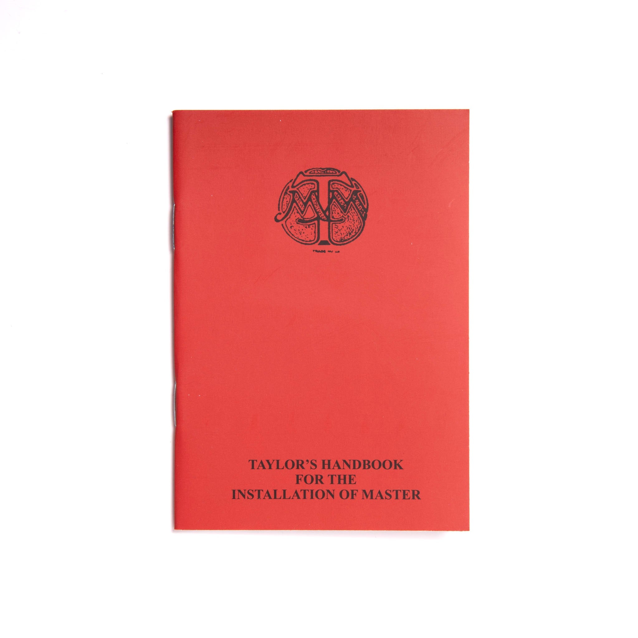 A red booklet with a Masonic symbol printed on the cover, titled 'Taylor's Handbook for the Installation of Master'.