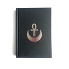 A hardback Masonic book with a black cover featuring a silver emblem of an ankh in a crescent moon.