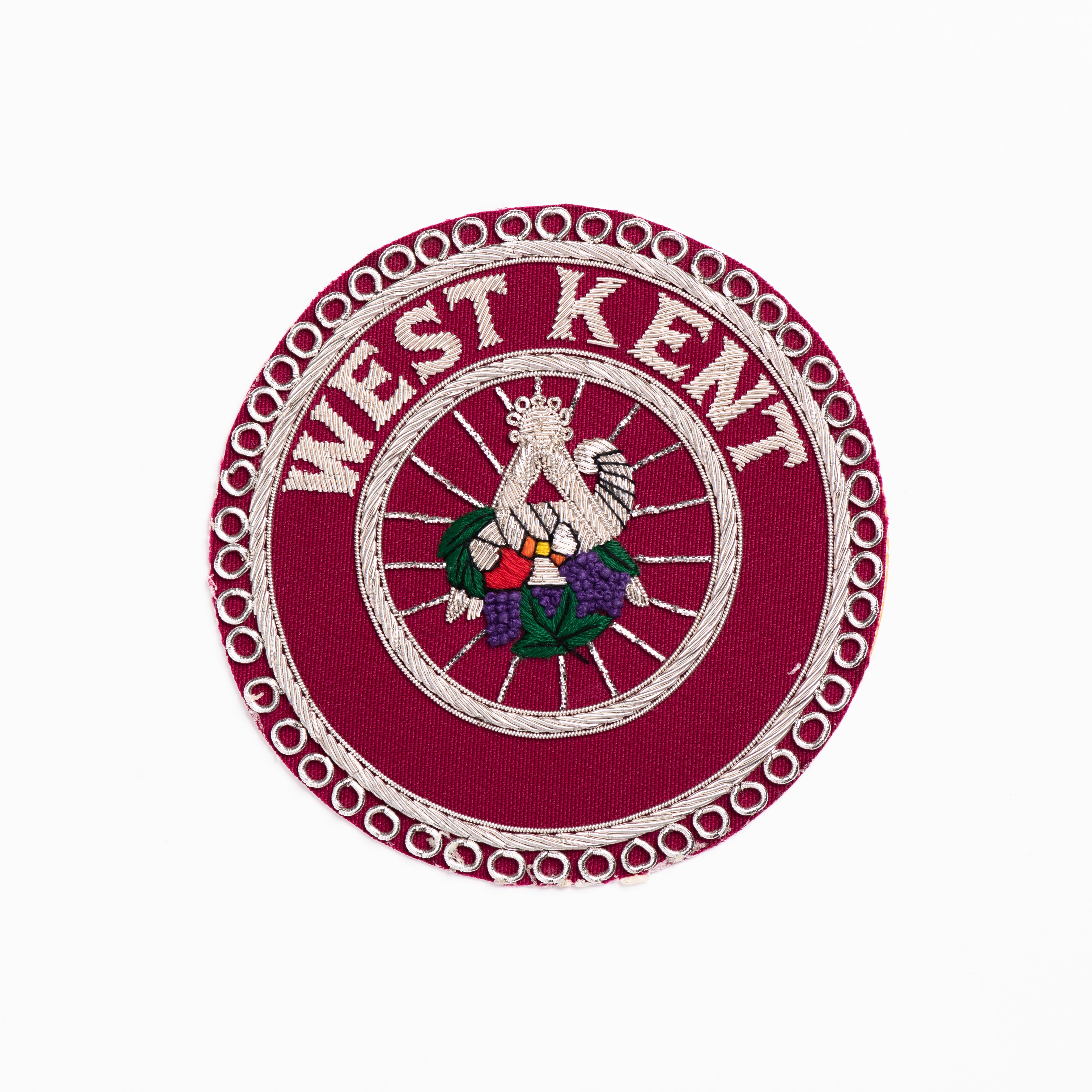 A Craft Provincial & District Steward's Masonic Apron Badges circular embroidered with the text 'WEST KENT' and an emblem in the center, predominantly red with white and green details.