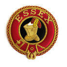 A circular red, gold, black, and white embroidered badge with the word 'ESSEX' in the center and a figure wearing a boot and holding a arrow.
