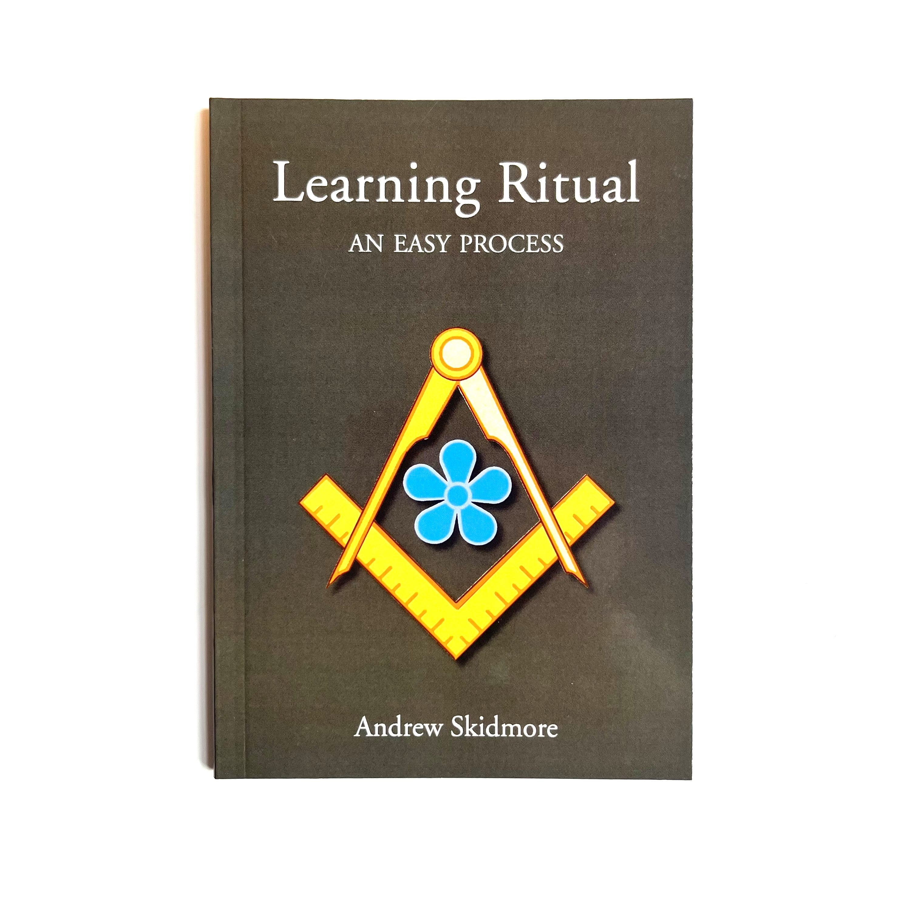 A Masonic book cover with a title 'Learning Ritual: An Easy Process' by Andrew Skidmore. The cover features a simple design with a blue floral forget me not emblem and a square & compasses graphic.