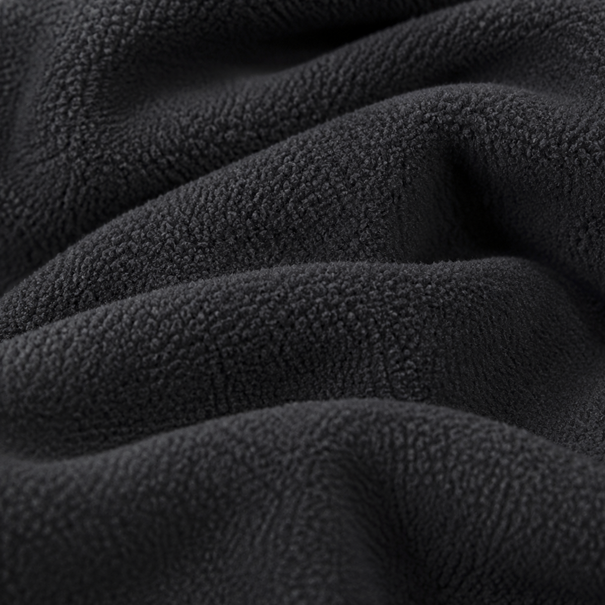 Close-up detail of black fleece fabric with soft textured fibres and gentle folds