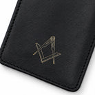 Close-up of gold square and compasses emblem on black leather glasses case