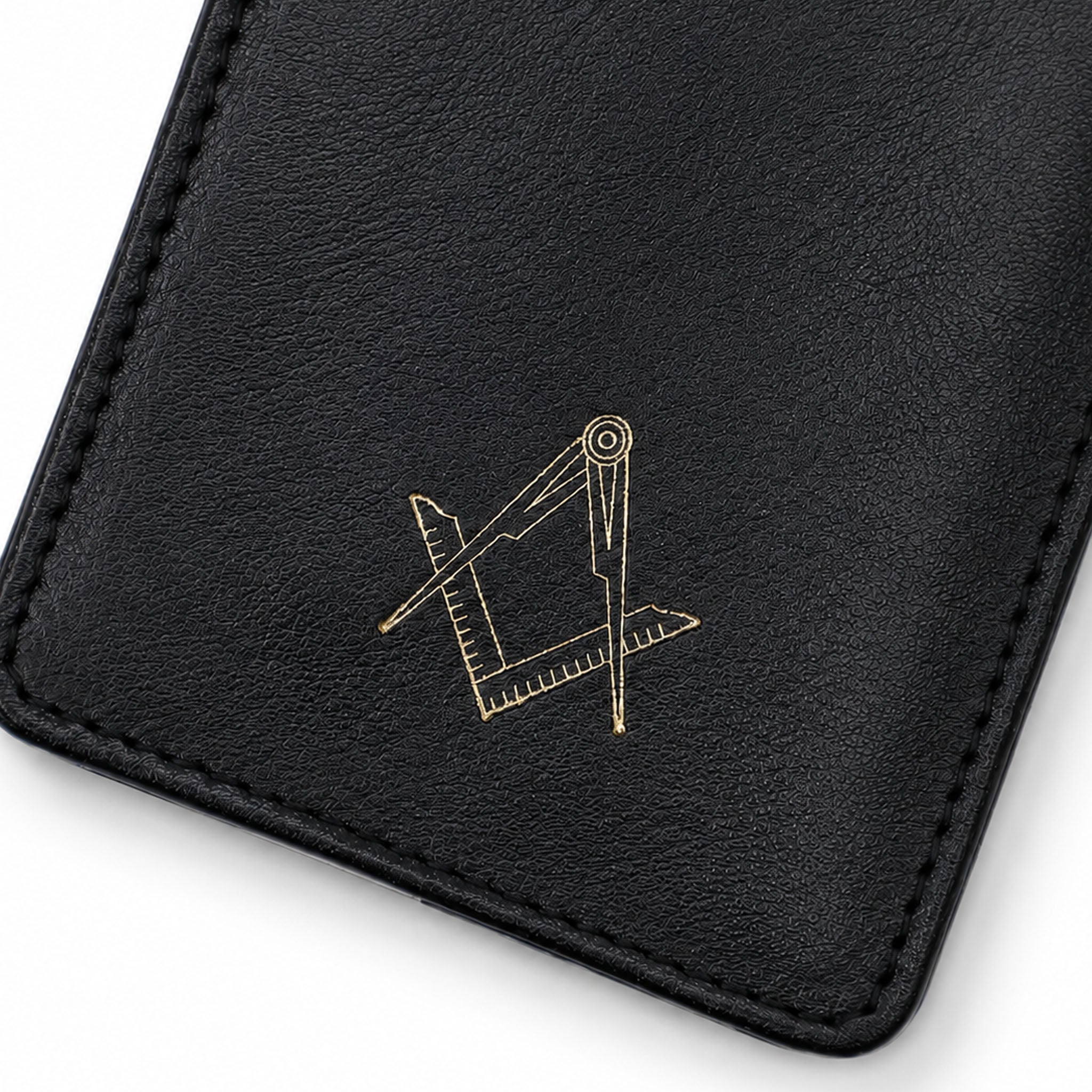 Close-up of gold square and compasses emblem on black leather glasses case