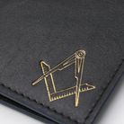 Close up view of black leather card holder wallet with stitched edges, featuring a gold Masonic square-and-compass emblem in the bottom corner.