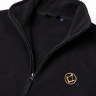 Close-up of black Masonic fleece gilet showing the open stand collar, black zipper, soft fleece texture, and gold and black square and compasses emblem on the left chest.