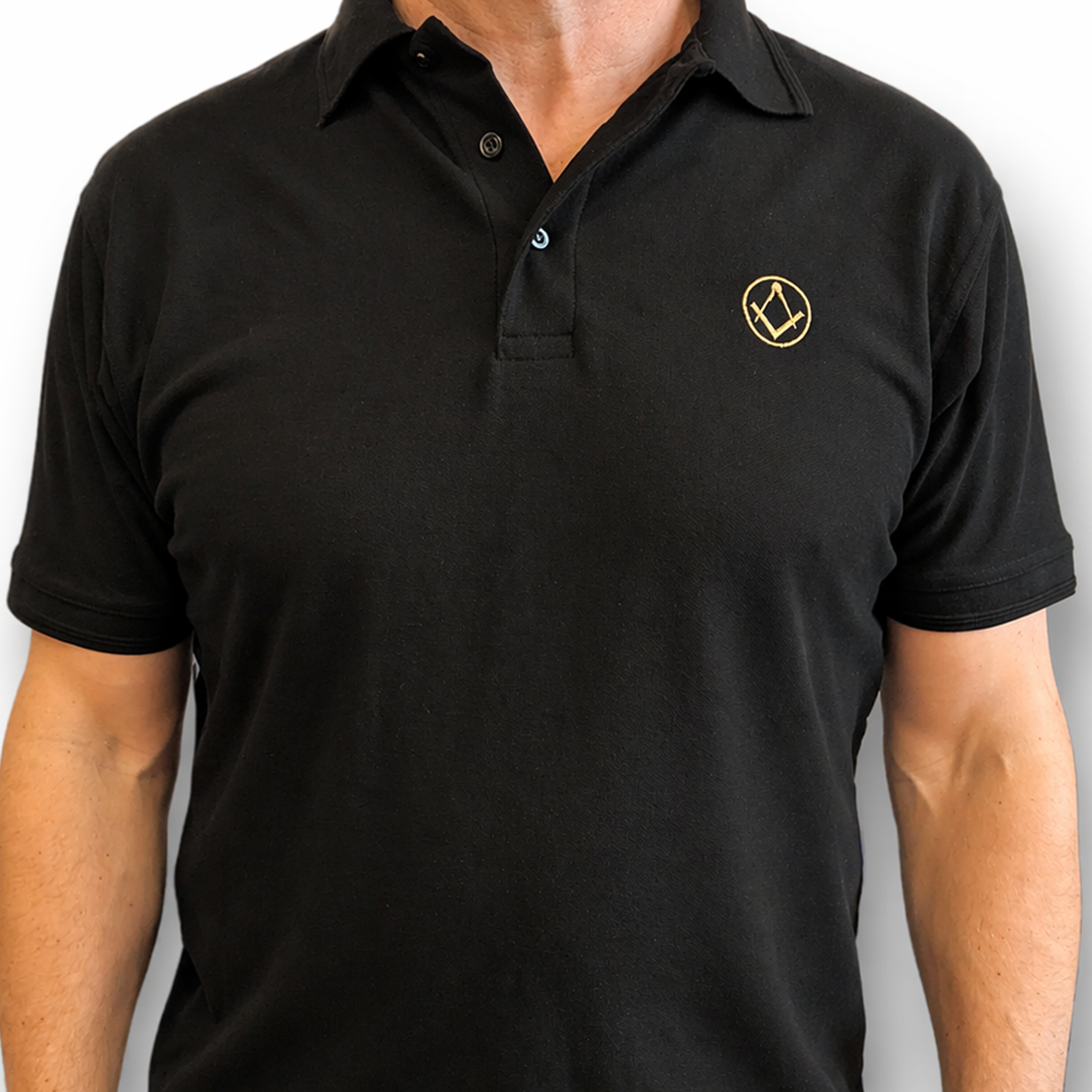 Model wearing black polo shirt with a collar and button placket, featuring a small gold embroidered Masonic square-and-compass symbol on the chest.