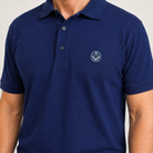 Model wearing blue polo shirt with a collar and button placket, featuring a small sliver and blue embroidered Masonic square-and-compass symbol on the chest.