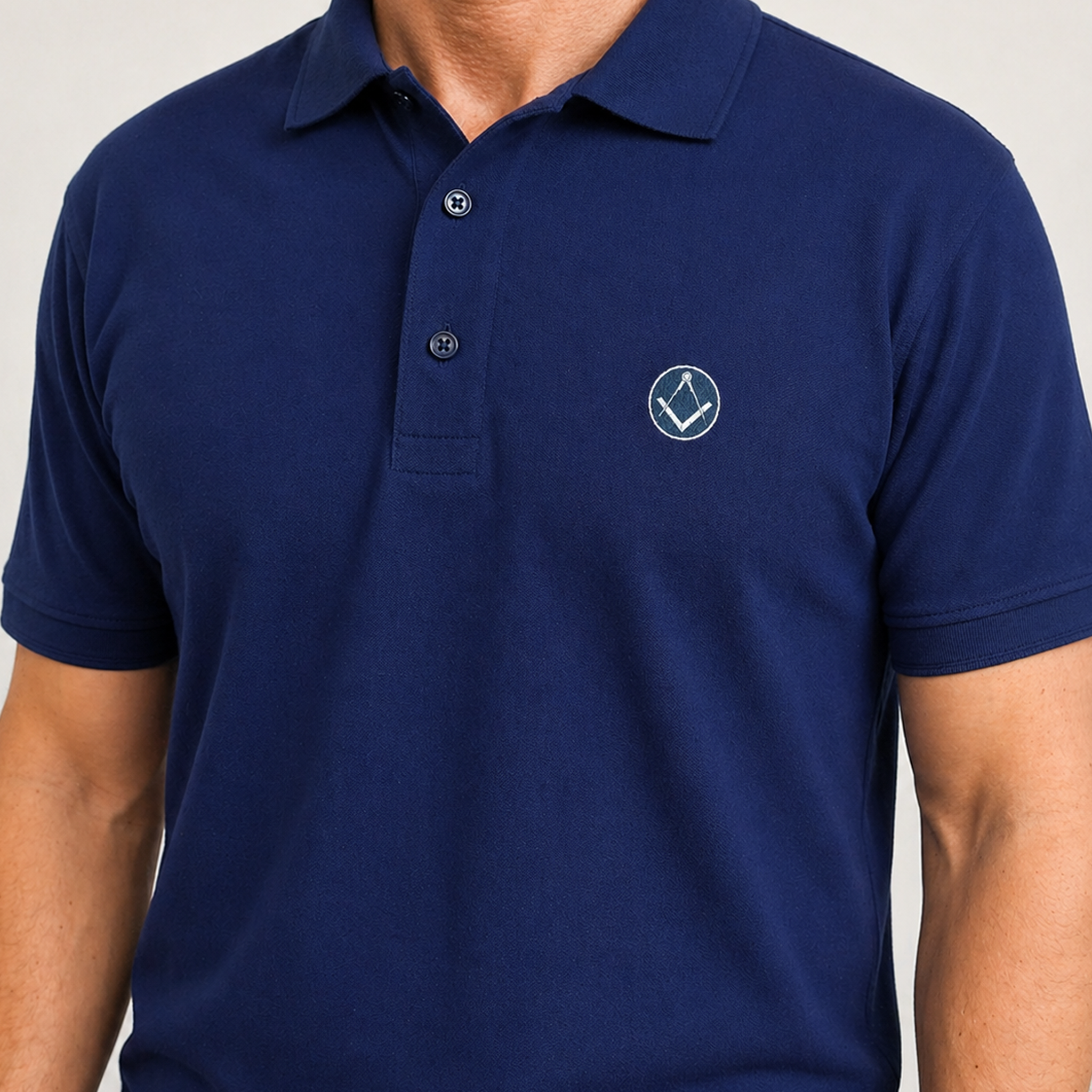 Model wearing blue polo shirt with a collar and button placket, featuring a small sliver and blue embroidered Masonic square-and-compass symbol on the chest.