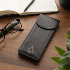 Black leather masonic glasses case on wooden desk with reading glasses and notebook