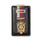 A Masonic black leather jewel pad with   golden coloued jewel and a striped red and blue ribbon.