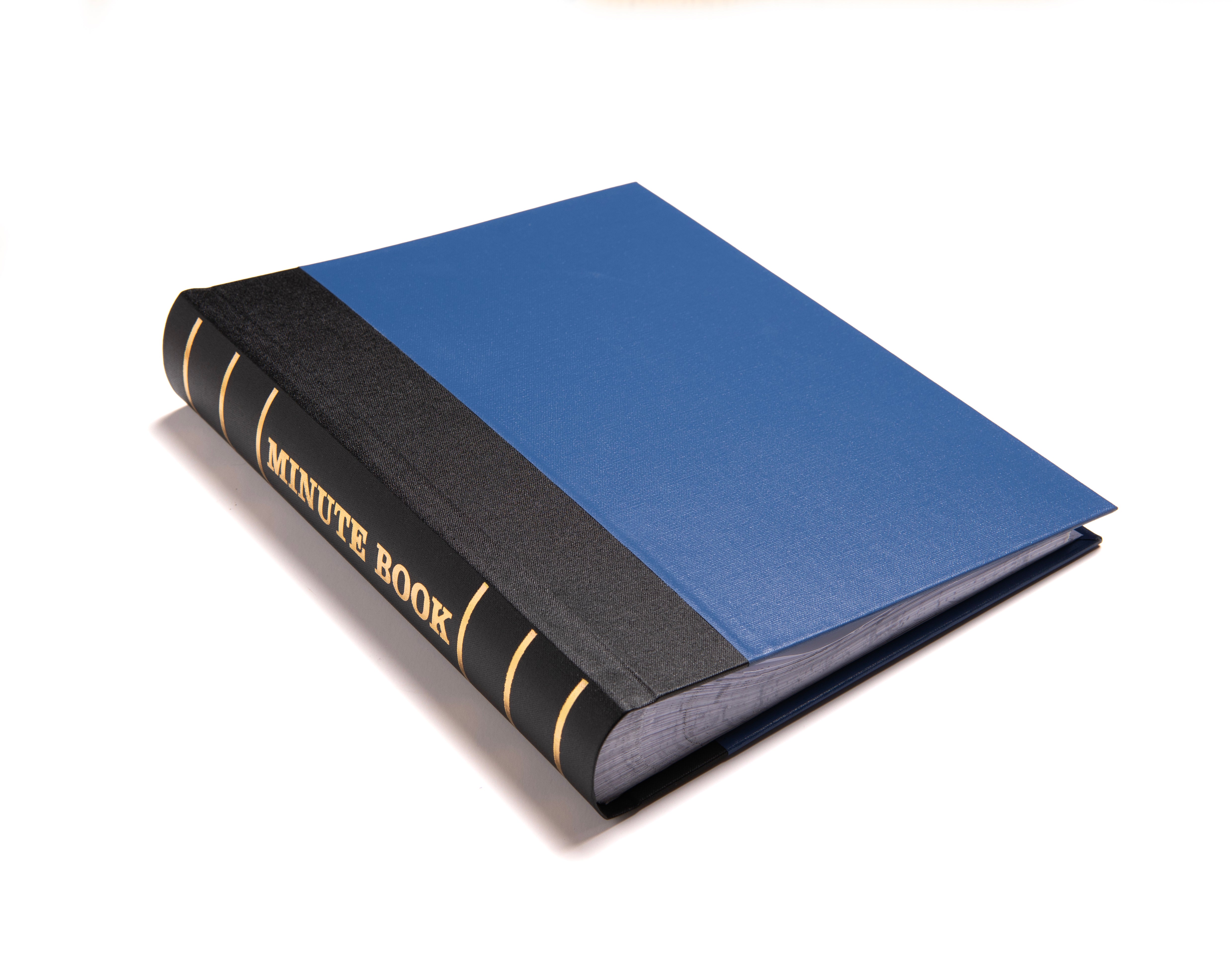 A bound Masonic minute book with a blue and black cover, the title 'MINUTE BOOK' is visible on the spine.