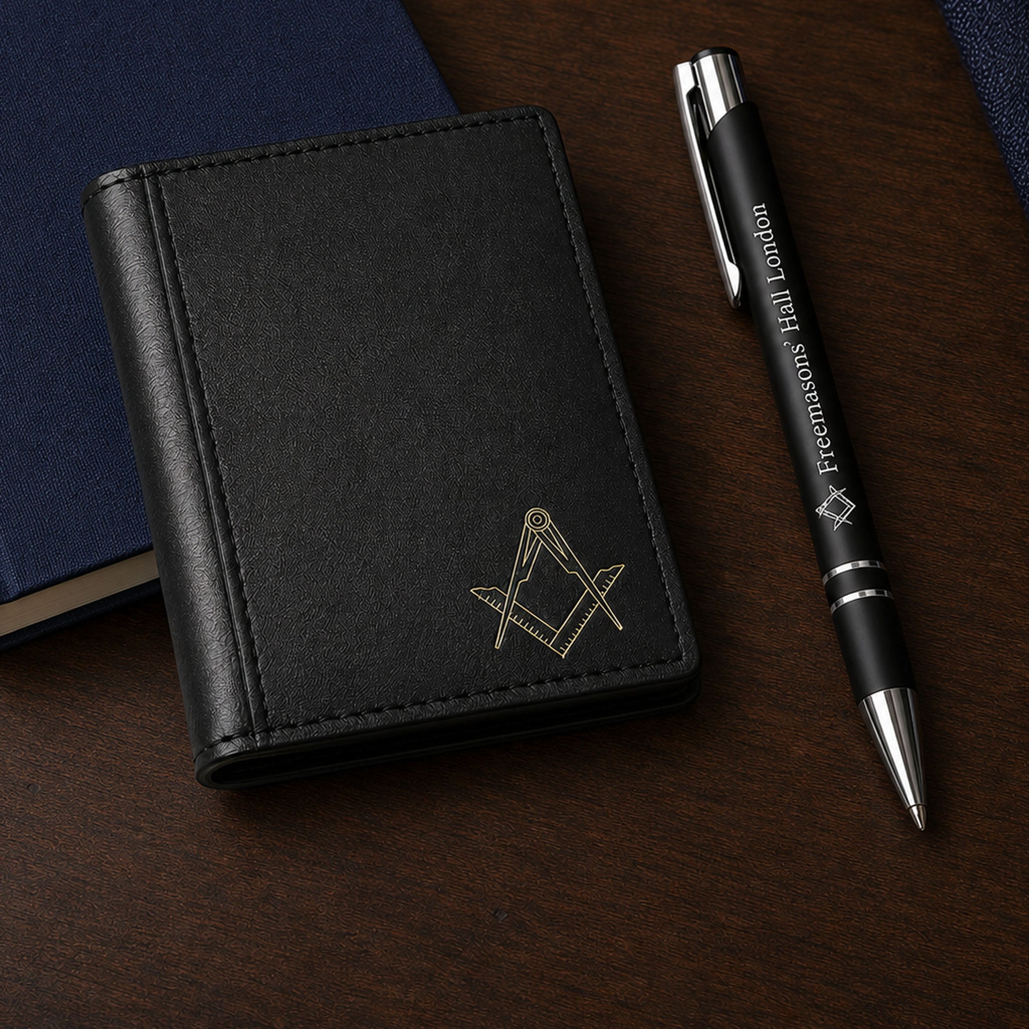 Black Masonic card holder with gold Square and Compasses symbol, displayed with a Freemasons’ Hall London pen.