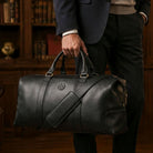 Black leather Masonic holdall being carried in a library setting