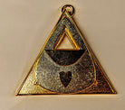 Gold Masonic Almoner triangular pendant with a heart design on a beige background