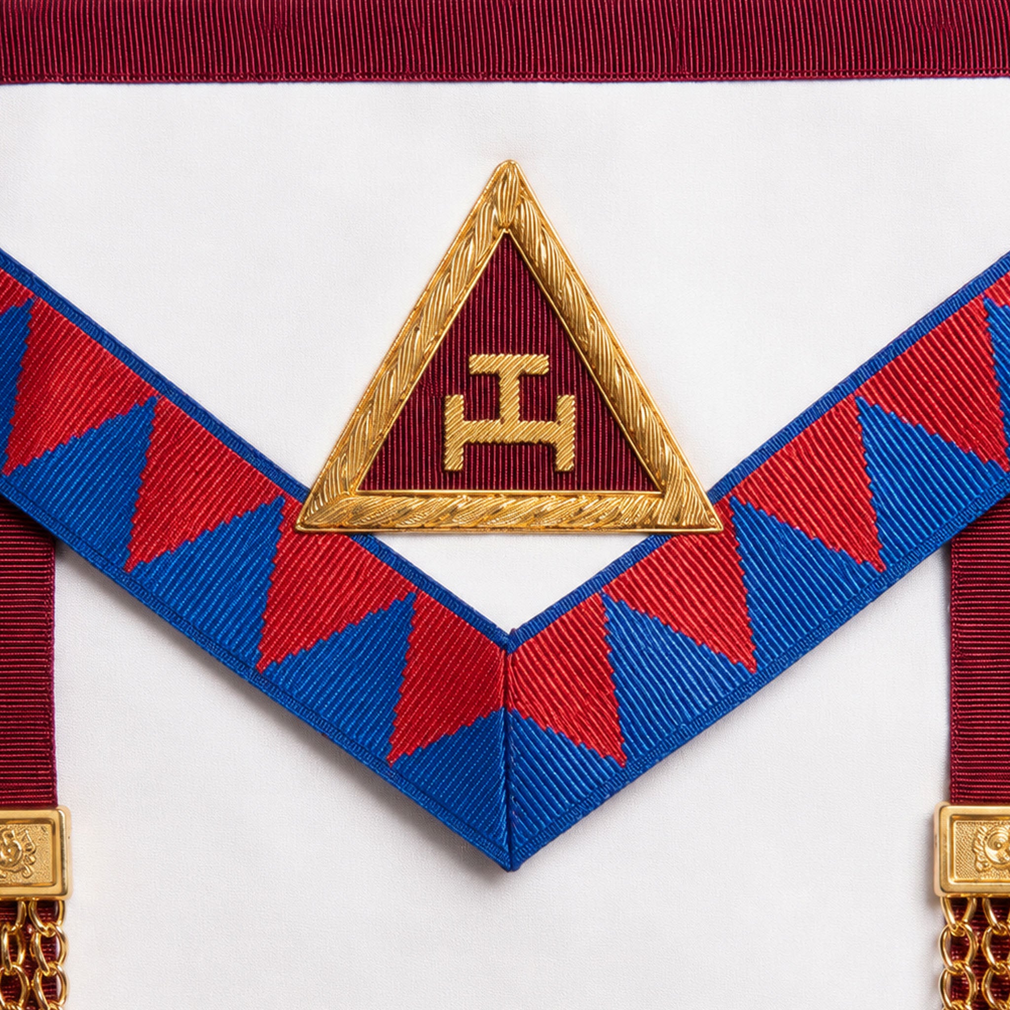 UGLE-approved Masonic Royal Arch Principal apron featuring a white and red front with a gold emblem, red and blue geometric patterns on the sides. Close up image of the Royal Arch symbol