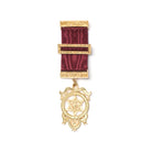 A gold-colored large Masonic breast jewel with a geometric pattern and a red ribbon attachment, displaying a symbolical design.