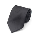 A black necktie with a geometric pattern, rolled up on a plain background.