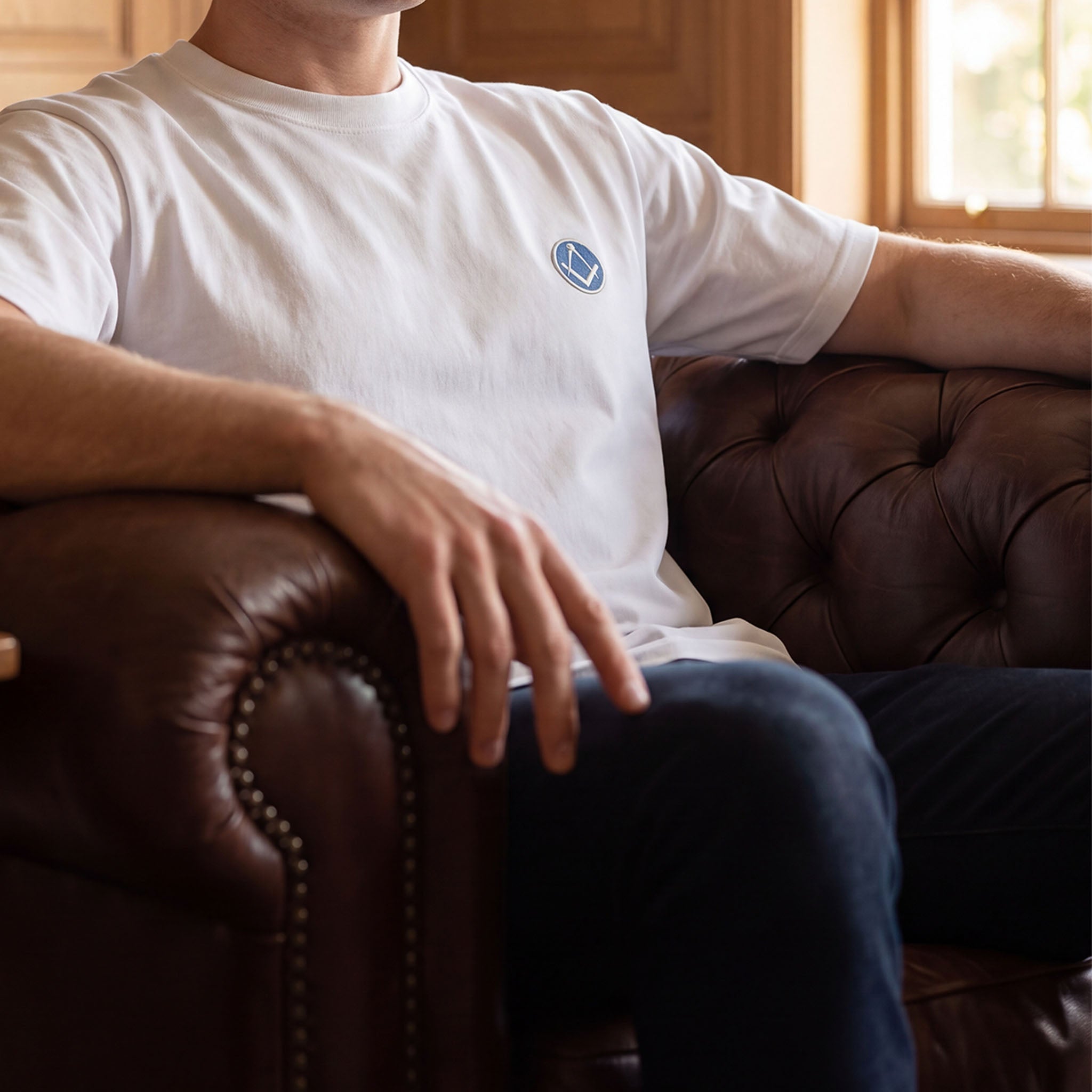 A Masonic premium white t-shirt featuring the square and compasses emblem on the left chest is being worn.
